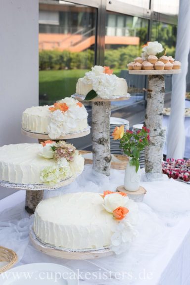 Vierteilige Hochzeitstorte mit floraler Deko auf Holzstämmen